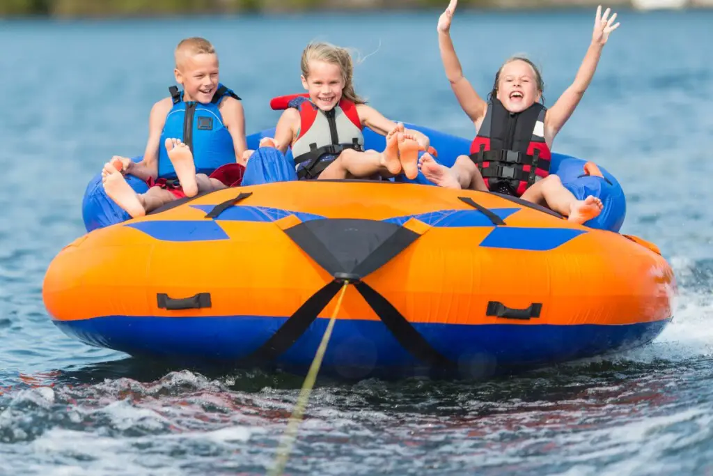 towing a tube with children behind a cuddy cabin boat on the water