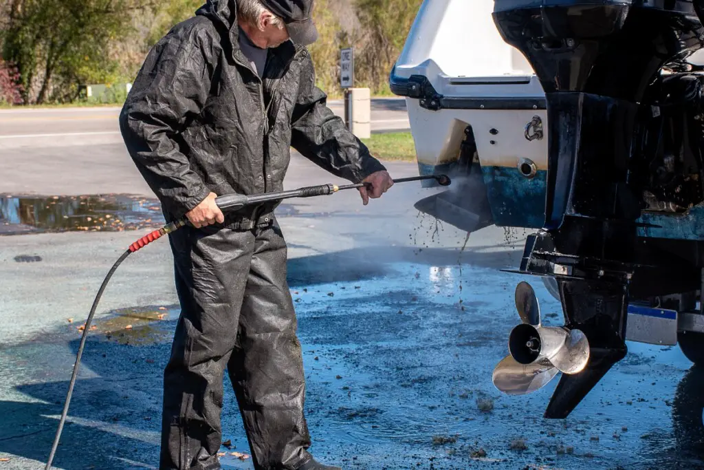 Image of man power washing the dirty transom of a boat