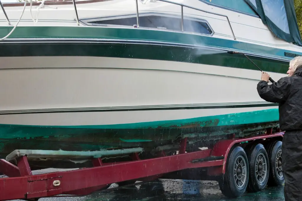 image of man power washing a fiberglass boat hull.