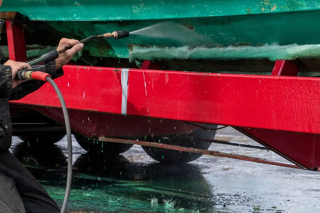 image of man power washing a boat's hull on a trailer.
